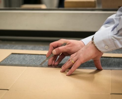 hands cutting cardboard to bespoke design