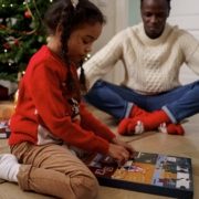 child opening advent calendar with dad and Christmas tree in background