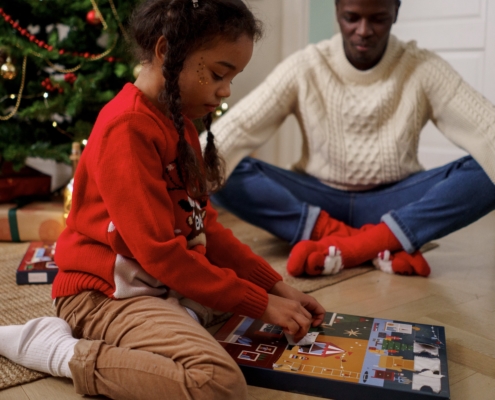 child opening advent calendar with dad and Christmas tree in background