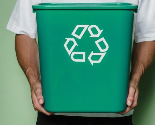 man-holding-green-bin-with-recycling-symbol-on