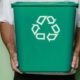 man-holding-green-bin-with-recycling-symbol-on