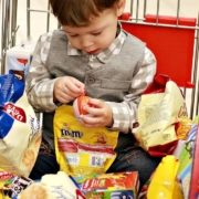 boy-in-supermarket-trolley-surrounded-by-bright-food-packaging