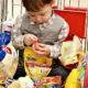 boy-in-supermarket-trolley-surrounded-by-bright-food-packaging